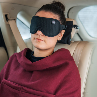 Close up view of a woman sleeping wearing her travel blanket and ALLasleep travel accessory