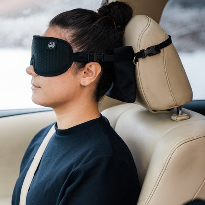 Woman sleeping seated in a car with the ALLasleep travel accessory