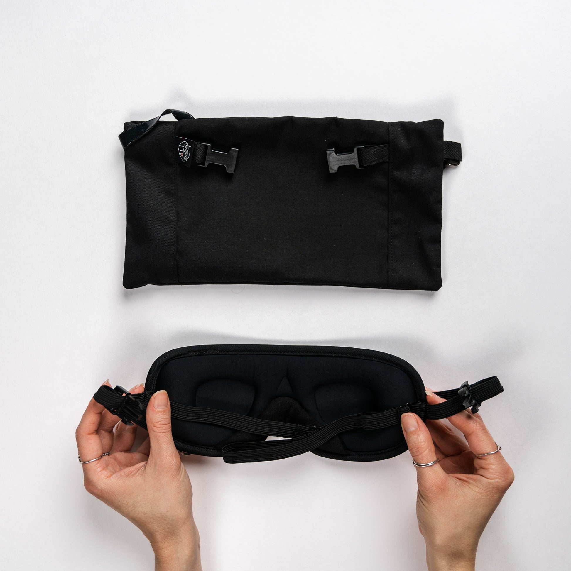 Top view of the headrest pouch and a pair of hands showing the backside of the eye mask.